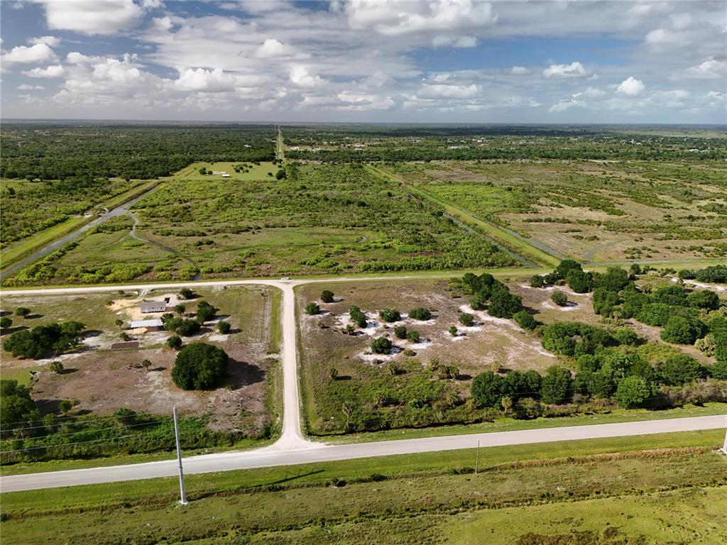 An aerial view shows a rural landscape with a dirt road intersecting a paved road — 16734 NW 242ND STREET, OKEECHOBEE, FL