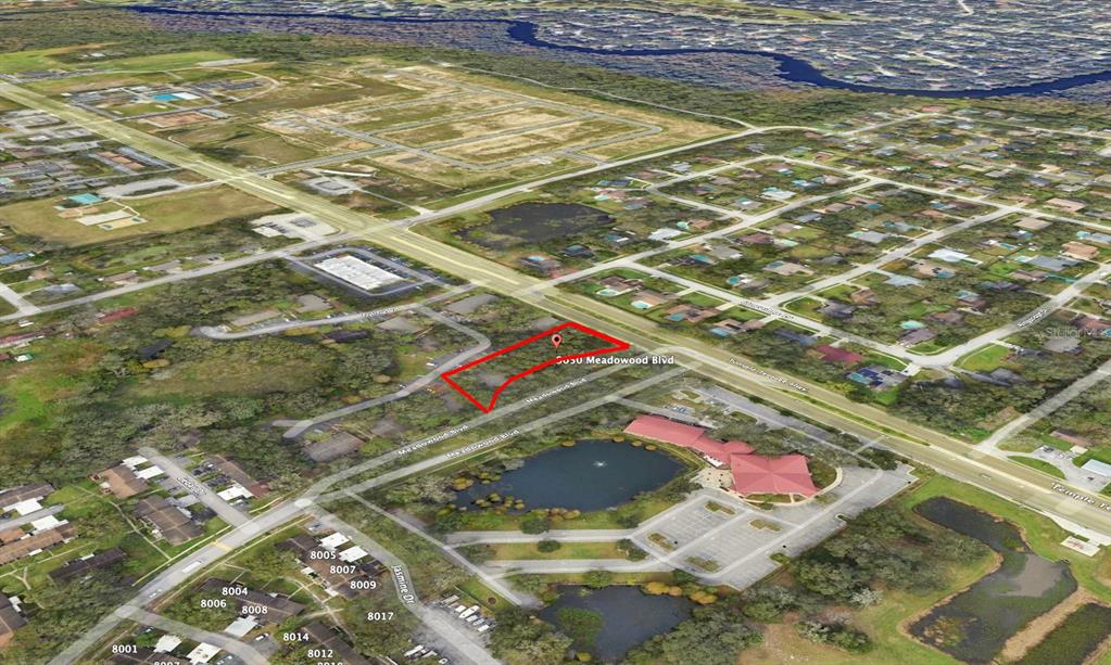 An aerial view shows a vacant, red-outlined lot located along a paved road — 9050 MEADOWOOD BOULEVARD, TEMPLE TERRACE, FL