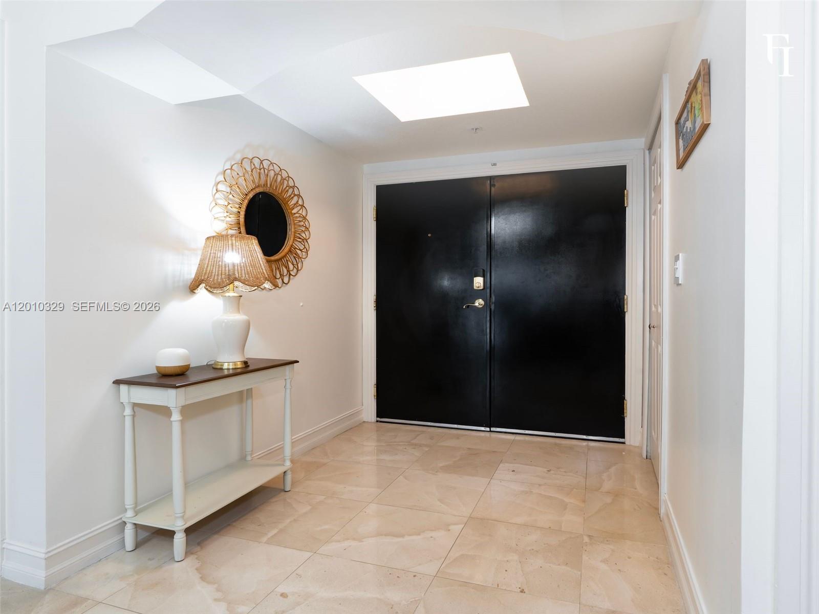 A foyer features a black double door, tile flooring, and a console table with lamp — 322 Madeira Ave # 405, Coral Gables FL 33134, CORAL GABLES, FL