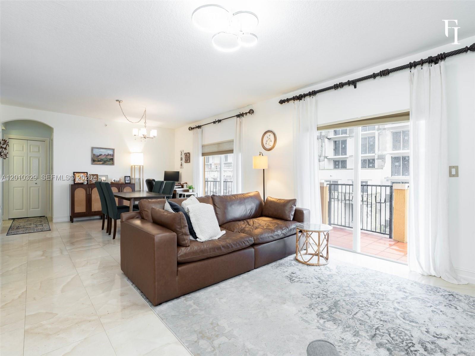 A living room with a brown leather sofa, tile floors, and a balcony view — 322 Madeira Ave # 405, Coral Gables FL 33134, CORAL GABLES, FL