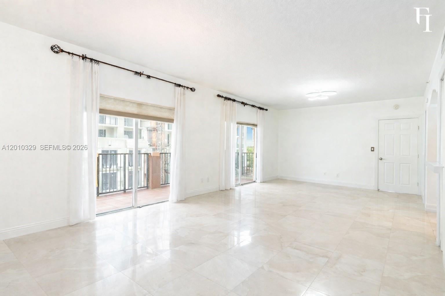 A bright, empty living room features white walls, light tile flooring, and two sliding glass doors — 322 Madeira Ave # 405, Coral Gables FL 33134, CORAL GABLES, FL