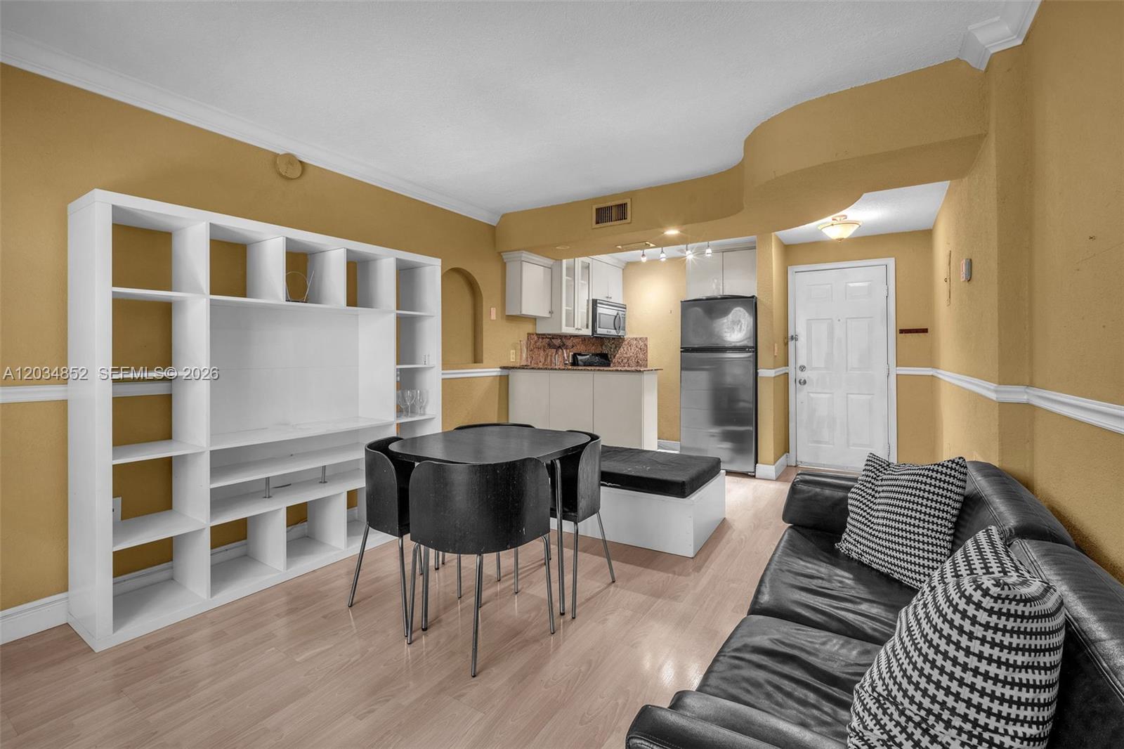 A living room features a white shelving unit, a dining table, and a black sofa — 3245 Virginia St # 65, Miami FL 33133, MIAMI, FL