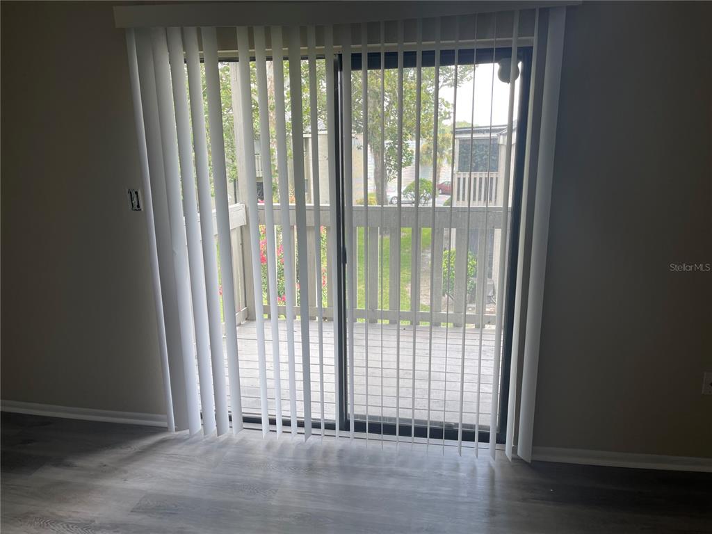 A sliding glass door with vertical blinds opens onto a wooden balcony — 137 SPRINGWOOD CIRCLE UNIT D, LONGWOOD, FL