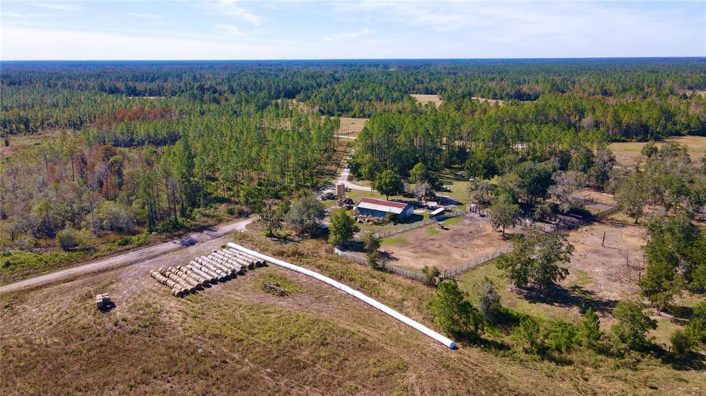 An aerial view shows a rural property with a barn, fenced pastures, and hay bales — 5656 NE US HIGHWAY 27, CHIEFLAND, FL