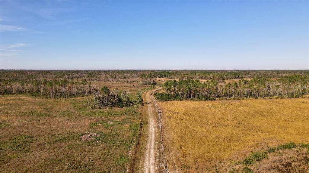 An aerial view shows a dirt path cutting through a large, flat, grassy rural landscape — 5656 NE US HIGHWAY 27, CHIEFLAND, FL