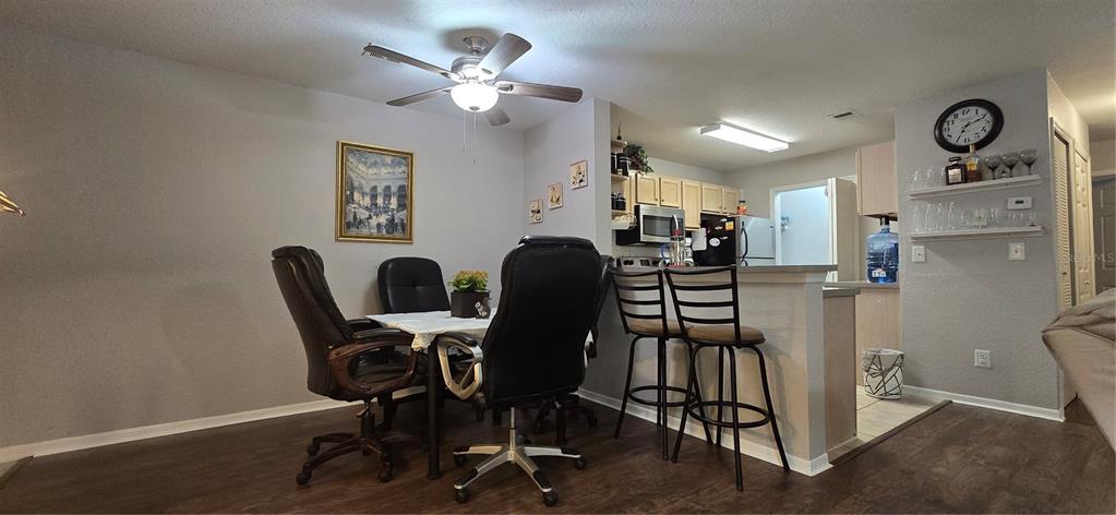 A dining area with a table and chairs sits adjacent to a kitchen breakfast bar — 7606 PISSARRO DRIVE UNIT 14106, ORLANDO, FL