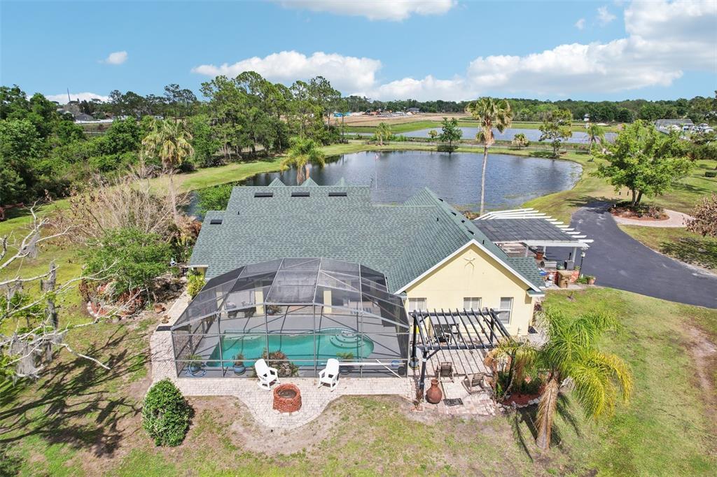 An aerial view of a house with a pool enclosure, patio, and a backyard pond — 3954 MCCLELLAND ROAD, ST CLOUD, FL