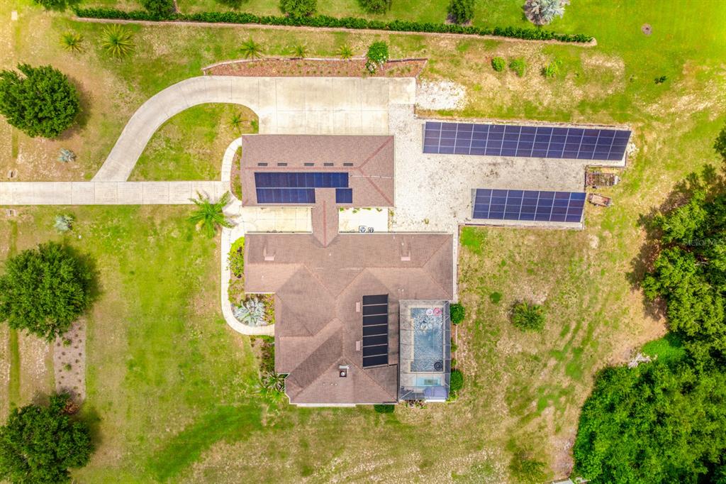 An aerial view shows a house with solar panels on the roof and a pool — 27324 GRAND OAK LANE, TAVARES, FL