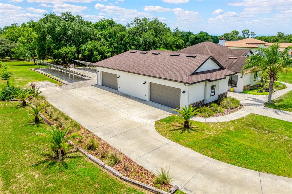 An aerial view shows a house with a two-car garage and a solar panel array — 27324 GRAND OAK LANE, TAVARES, FL