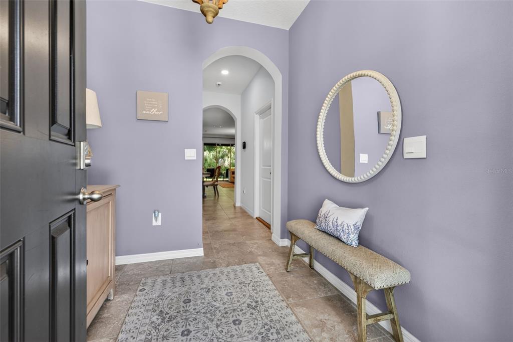 An entryway features light purple walls, a bench, a round mirror, and tile flooring — 6544 CALYPSO CORAL LANE, SARASOTA, FL