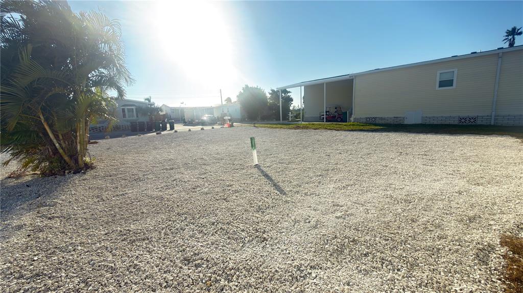 A gravel lot sits beside a mobile home with a palm tree in the foreground — 2858 TRINIDAD WAY, PALMETTO, FL