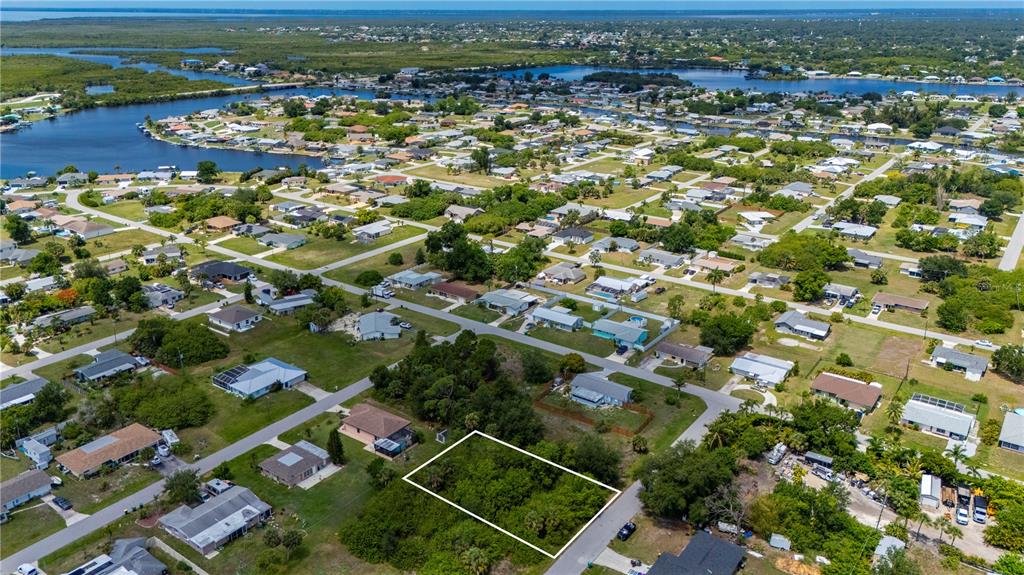 An aerial view shows a vacant, rectangular lot outlined in white within a suburban neighborhood — 209 FORREST AVENUE NW, PORT CHARLOTTE, FL