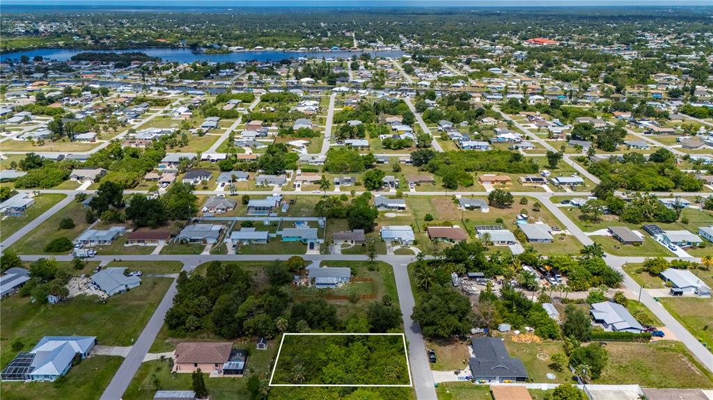 An aerial view shows a vacant, rectangular lot outlined in white within a residential neighborhood — 209 FORREST AVENUE NW, PORT CHARLOTTE, FL