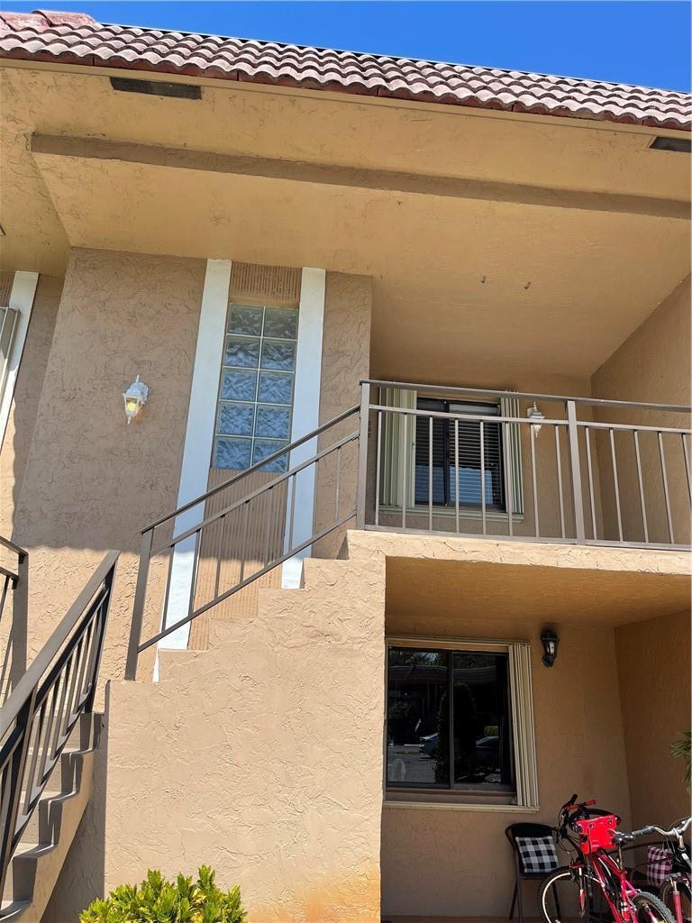 Exterior view of a two-story stucco building with a metal staircase and glass block accents — 197 Lakeview Drive # 202, Weston FL 33326, WESTON, FL