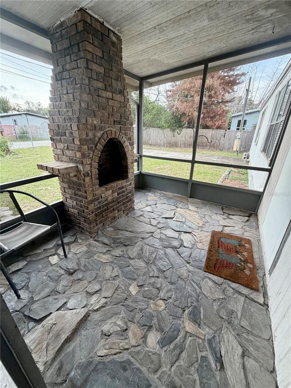 A screened-in porch features a stone floor and a prominent brick fireplace — 820 WATER OAKS DRIVE, WINTER HAVEN, FL