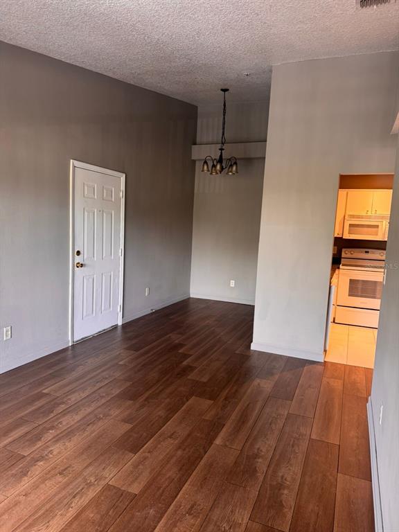 A room with wood-look flooring, a white door, a hanging light fixture, and an adjacent kitchen — 1132 S PINE RIDGE CIRCLE UNIT 32, SANFORD, FL