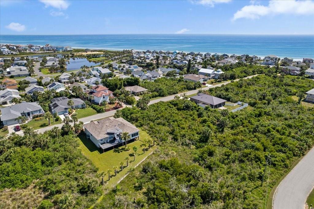 An aerial view shows a coastal neighborhood with houses surrounded by dense green vegetation — 16 MAHOE DRIVE N, PALM COAST, FL