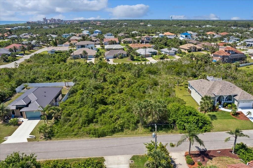 An aerial view shows a vacant, wooded residential lot situated between two existing houses — 16 MAHOE DRIVE N, PALM COAST, FL