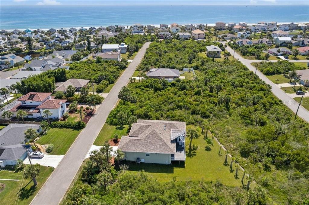An aerial view shows a house with a shingled roof surrounded by dense coastal vegetation — 16 MAHOE DRIVE N, PALM COAST, FL