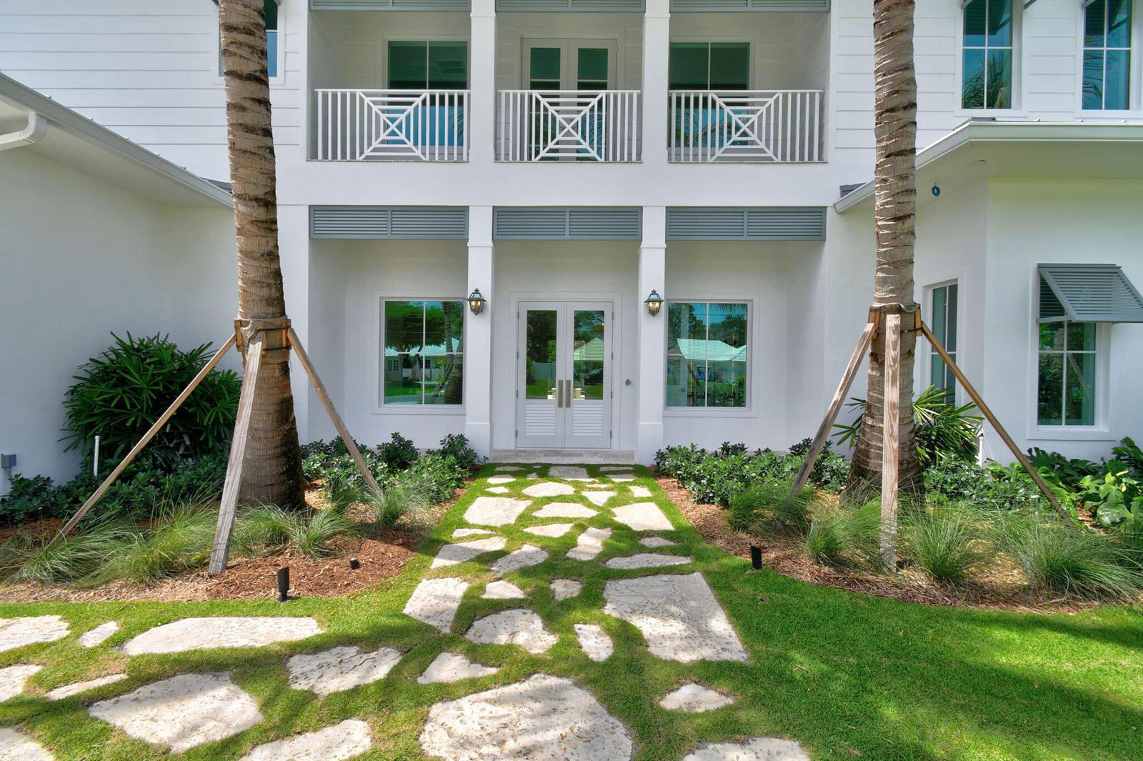 A white two-story house features a stone walkway leading to a double-door front entrance — 91 Golfview Drive, Tequesta FL 33469, TEQUESTA, FL