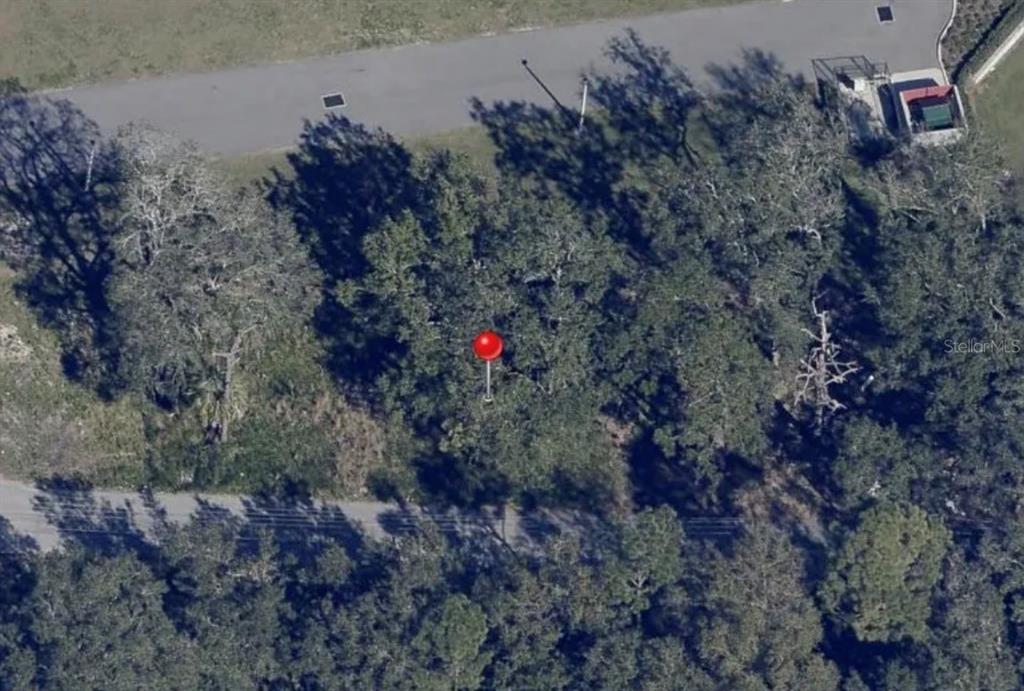This aerial view shows a wooded lot marked with a red pin near a road — BARN STREET, KISSIMMEE, FL