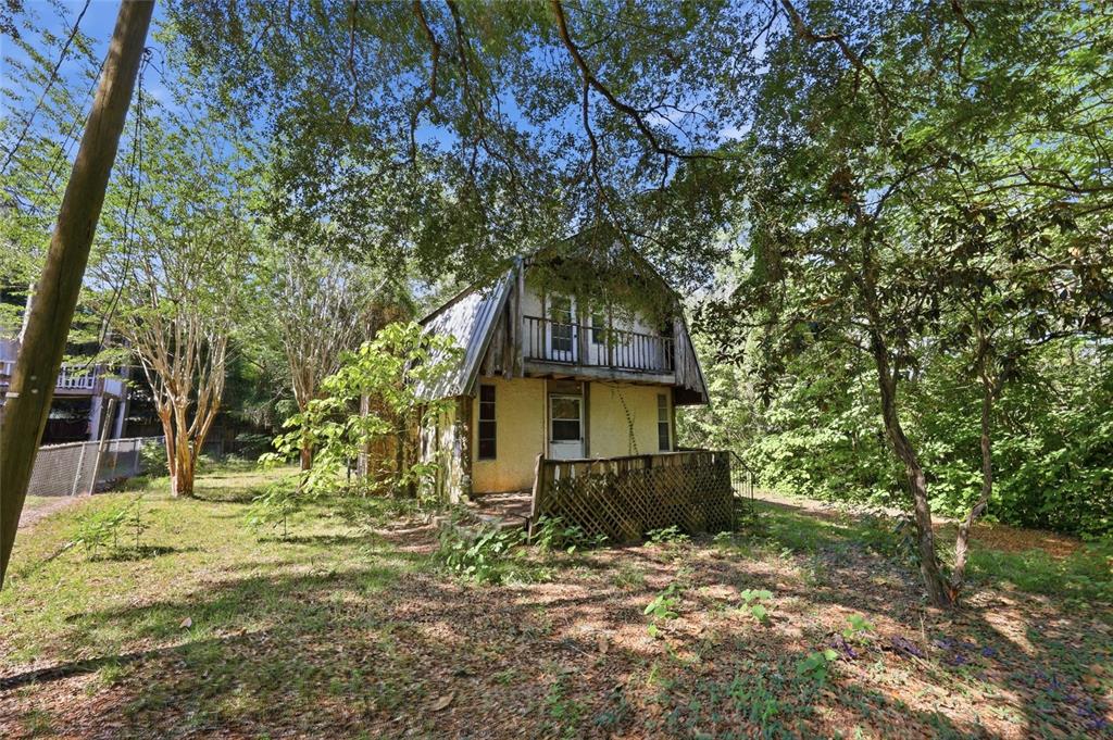 A two-story house with a balcony and a wooden deck stands among many trees — 20224 SE 156TH PLACE, UMATILLA, FL