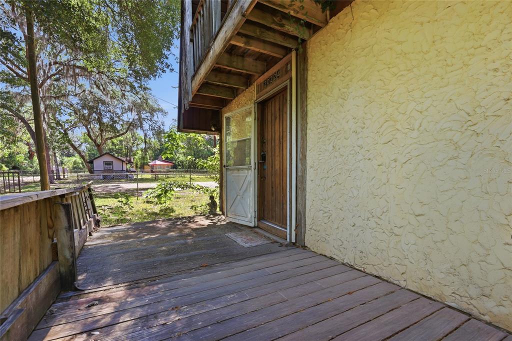 A wooden deck leads to a front door with a screen door on a house — 20224 SE 156TH PLACE, UMATILLA, FL
