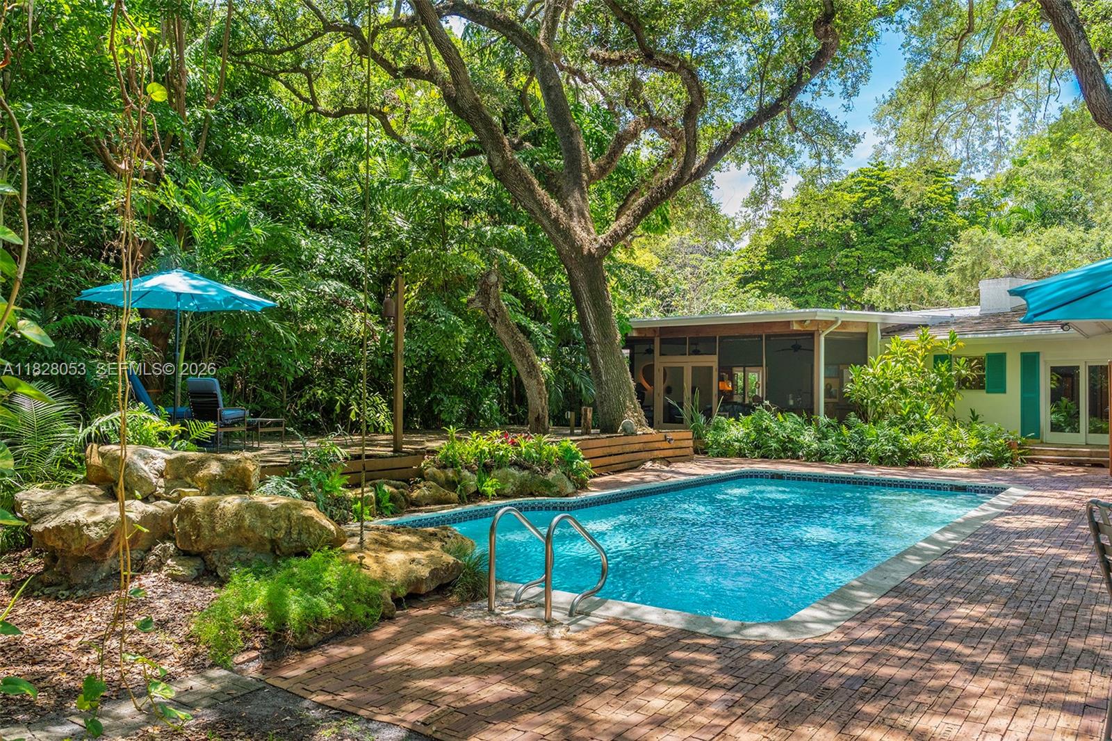 A backyard swimming pool with a brick patio, lush landscaping, and a screened-in porch — 3540 N Moorings Way, Miami FL 33133, MIAMI, FL