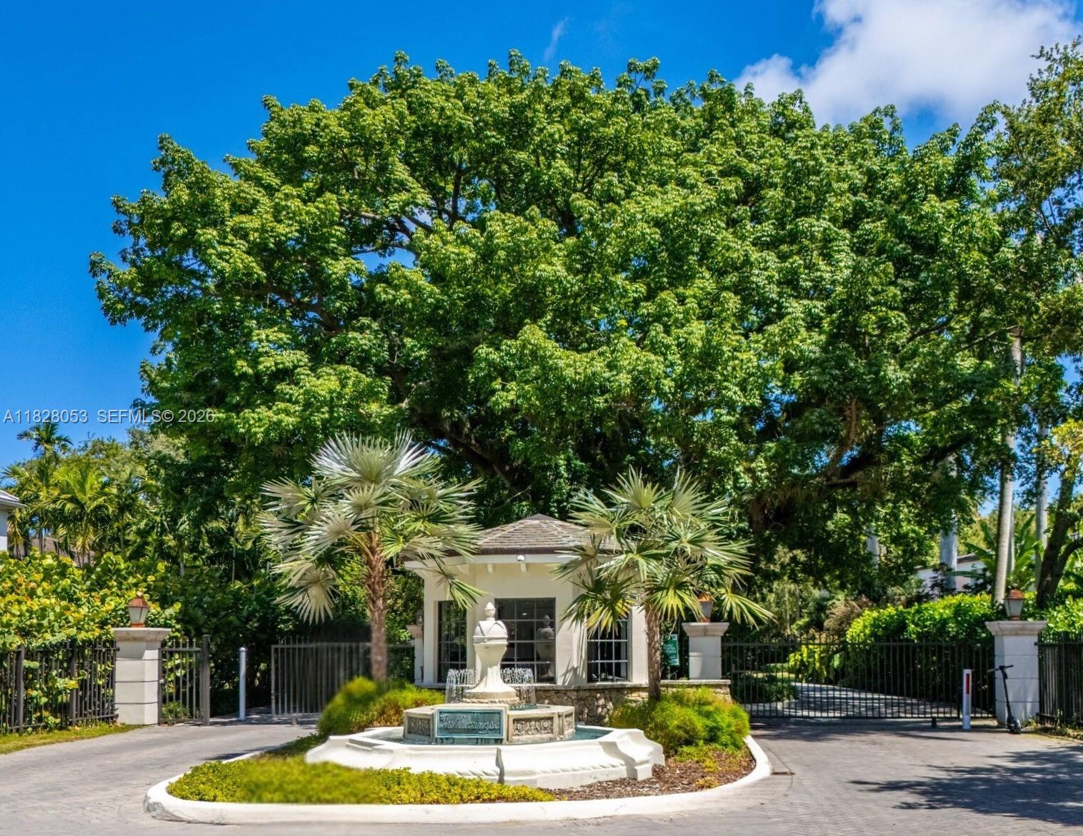 A gated entrance features a stone fountain, two palm trees, and a large shade tree — 3540 N Moorings Way, Miami FL 33133, MIAMI, FL