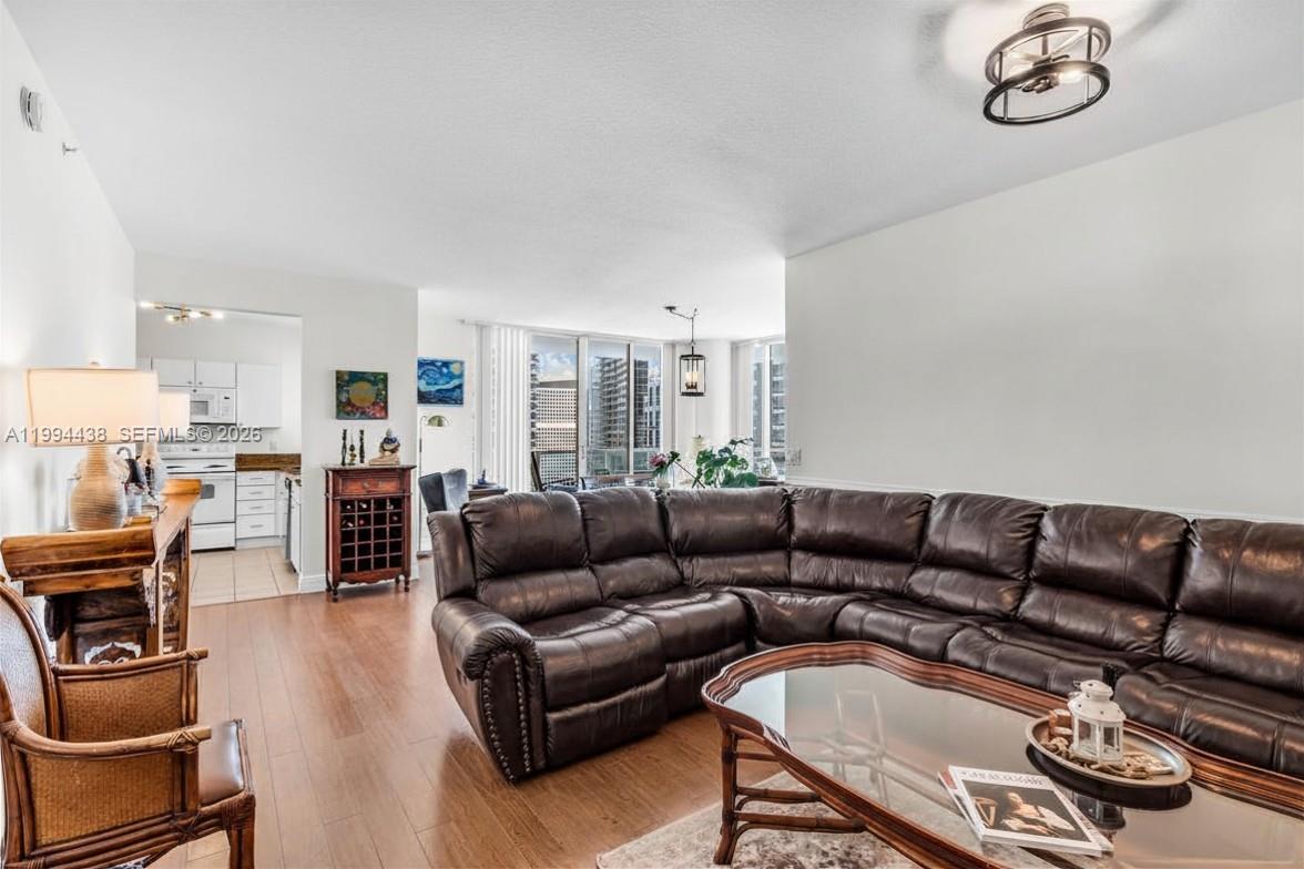 A living room features a large brown leather sectional, a glass coffee table, and hardwood floors — 1250 S Miami Ave # 3206, Miami FL 33130, MIAMI, FL