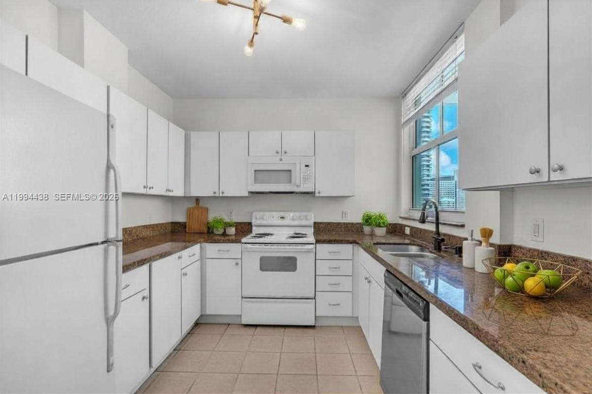 A kitchen features white cabinets, granite countertops, a white stove, and a stainless steel dishwasher — 1250 S Miami Ave # 3206, Miami FL 33130, MIAMI, FL