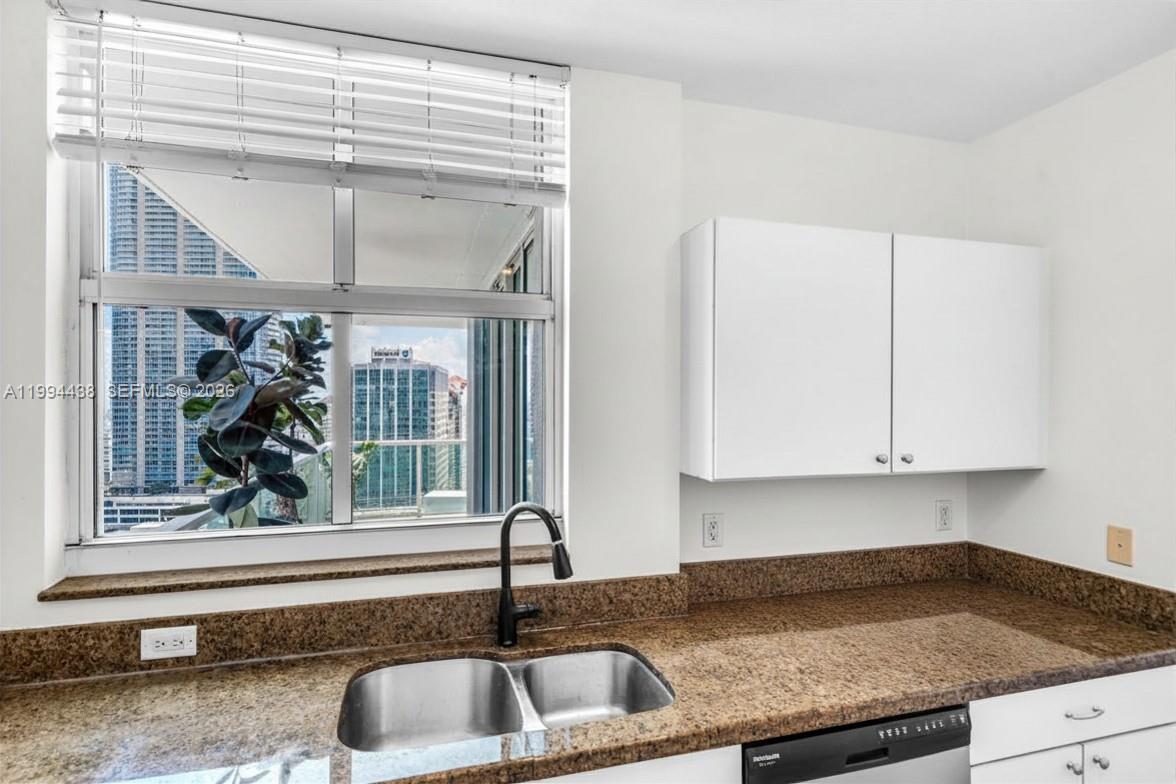 A kitchen sink with a dark faucet sits before a window overlooking city buildings — 1250 S Miami Ave # 3206, Miami FL 33130, MIAMI, FL