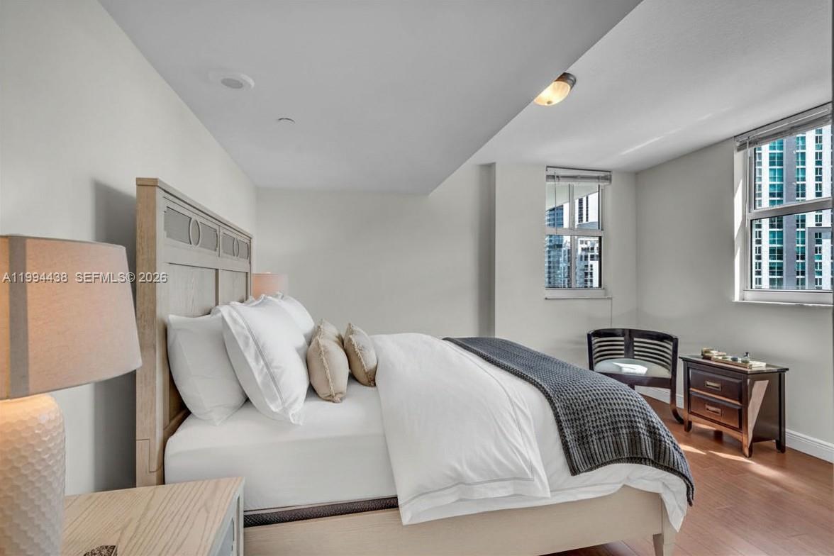 A bedroom features a wooden bed frame, white bedding, a dark nightstand, and city views — 1250 S Miami Ave # 3206, Miami FL 33130, MIAMI, FL