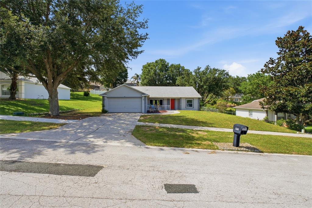 A single-story house with a gray exterior, a two-car garage, and a red front door — 993 SCENIC VIEW CIRCLE, MINNEOLA, FL
