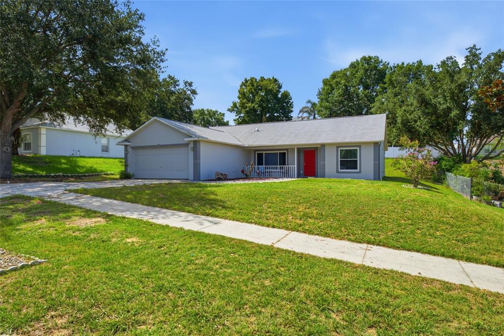 A single-story house with a gray exterior, a red front door, and a two-car garage — 993 SCENIC VIEW CIRCLE, MINNEOLA, FL