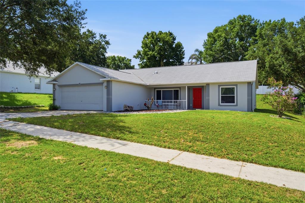 A single-story house with a gray exterior, a red front door, and a two-car garage — 993 SCENIC VIEW CIRCLE, MINNEOLA, FL