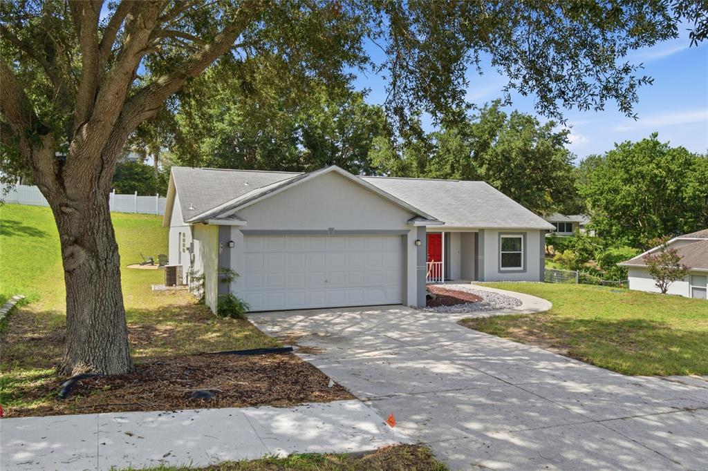 A single-story house with a gray exterior, a two-car garage, and a bright red door — 993 SCENIC VIEW CIRCLE, MINNEOLA, FL