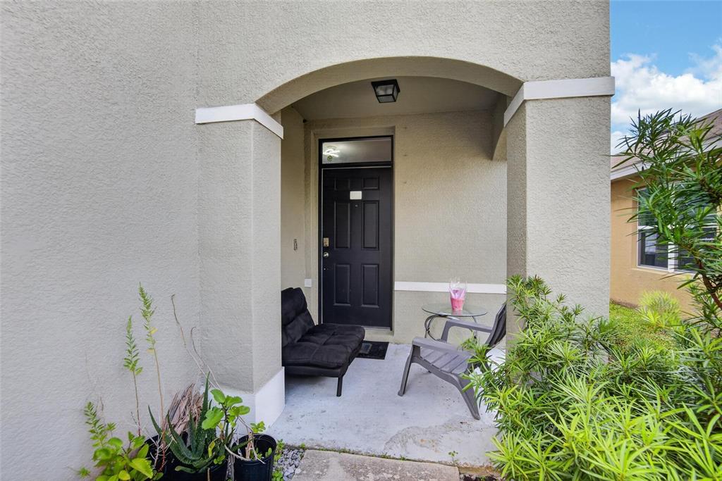 A covered entryway features a black front door, a small sofa, and a patio chair — 10231 GEESE TRAIL CIRCLE, SUN CITY CENTER, FL