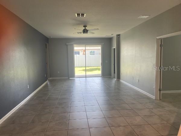 A spacious living area features light-colored tile flooring, gray walls, and a sliding glass door — 1125 SAGUARO STREET, HAINES CITY, FL