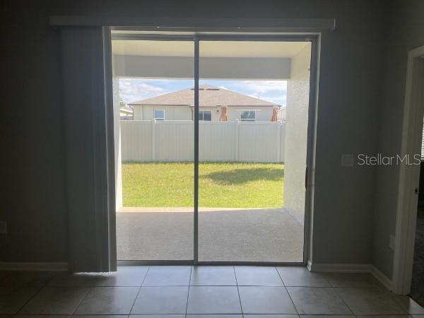 A view from inside a room through a sliding glass door to a fenced backyard — 1125 SAGUARO STREET, HAINES CITY, FL