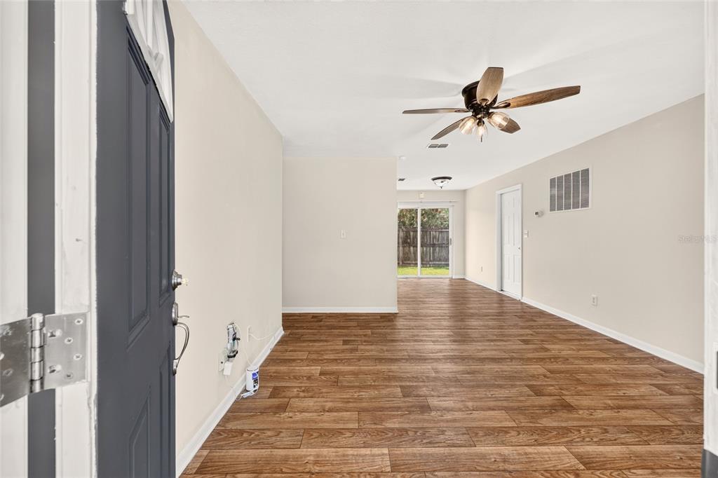 An interior view of a living room with wood-look flooring, a ceiling fan, and sliding doors — 3174 SE 6TH PLACE, OCALA, FL