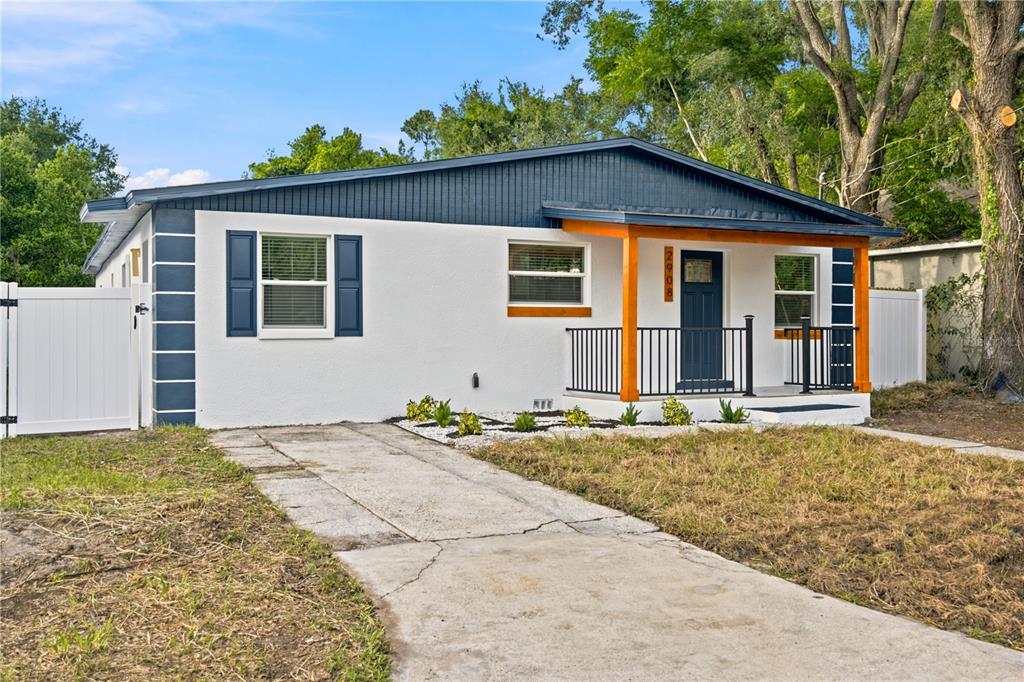 A single-story house with white stucco walls, a blue gable roof, and a front porch — 2908 E 26TH AVENUE, TAMPA, FL