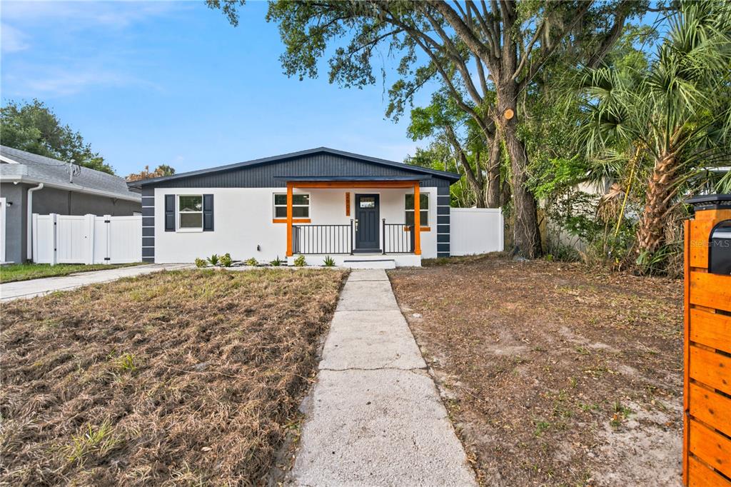A single-story house with a white exterior, dark trim, and a wooden front porch — 2908 E 26TH AVENUE, TAMPA, FL