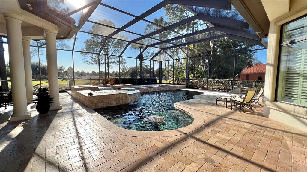 A screened-in patio features a swimming pool with a raised spa and stone pavers — 17784 SW 61ST LANE ROAD, DUNNELLON, FL