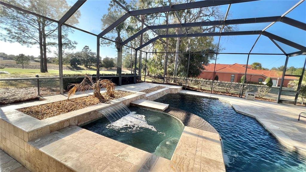 A screened-in pool and spa area with stone decking and a water feature — 17784 SW 61ST LANE ROAD, DUNNELLON, FL