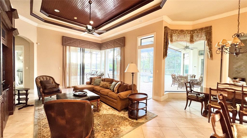 A living room features a coffered wood ceiling, tile floors, and large windows overlooking a pool — 17784 SW 61ST LANE ROAD, DUNNELLON, FL