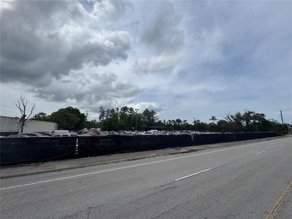 A fenced-in parking lot filled with numerous vehicles sits adjacent to a paved road — 5515/5517 SHAD ROAD, JACKSONVILLE, FL