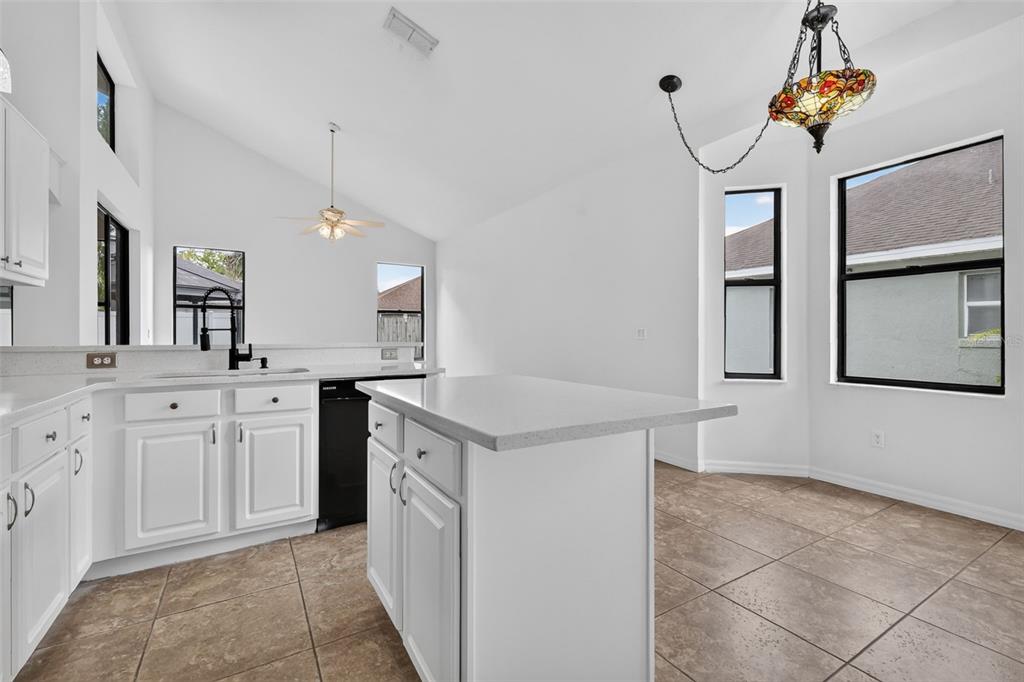 A kitchen with white cabinets, a central island, and a dining area with tile flooring — 12441 BOHANNON BOULEVARD, ORLANDO, FL