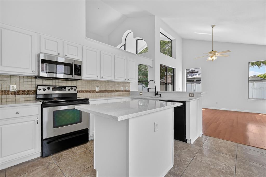 A kitchen with white cabinets, stainless steel appliances, a center island, and tiled flooring — 12441 BOHANNON BOULEVARD, ORLANDO, FL