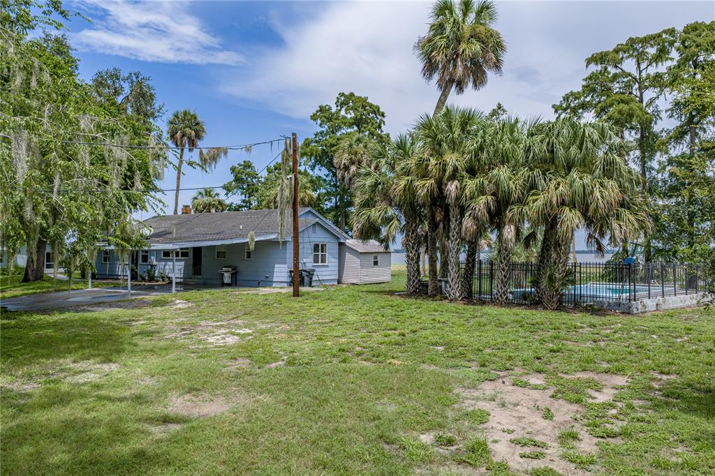 A blue house with a pool and palm trees sits on a grassy waterfront lot — 2901 KAYWORTH ROAD, LAKE WALES, FL